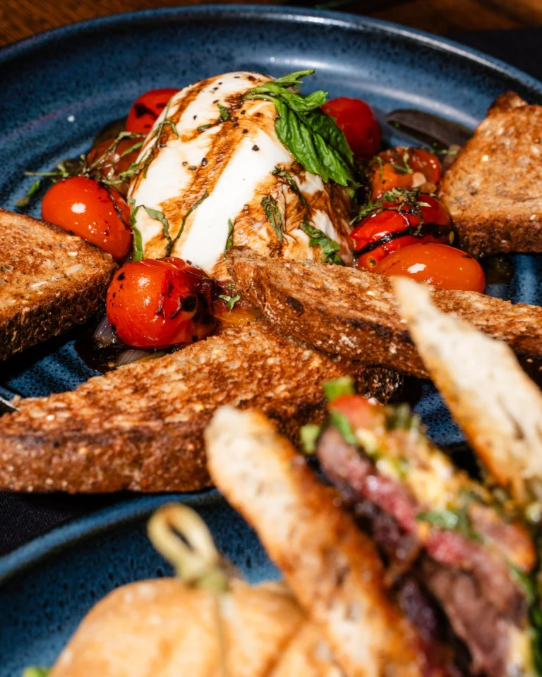Burrata with blistered tomatoes, basil and balsamic beside toasted rye