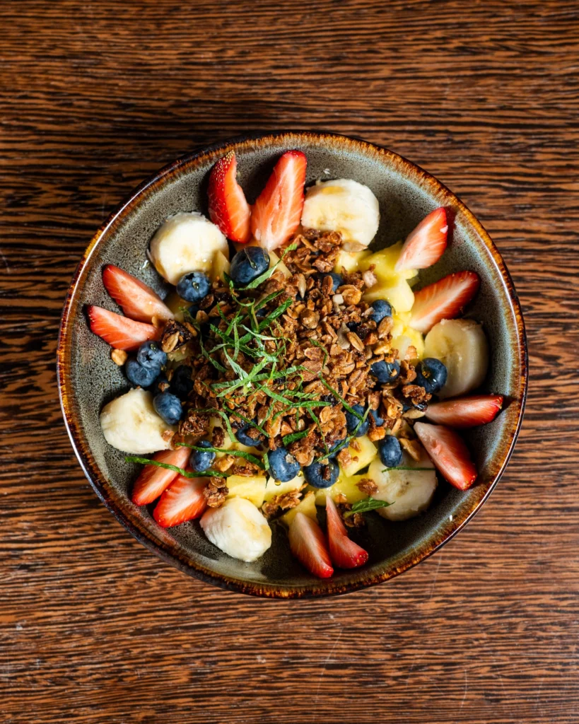Yogurt bowl with strawberries, banana, blueberries, granola and mint