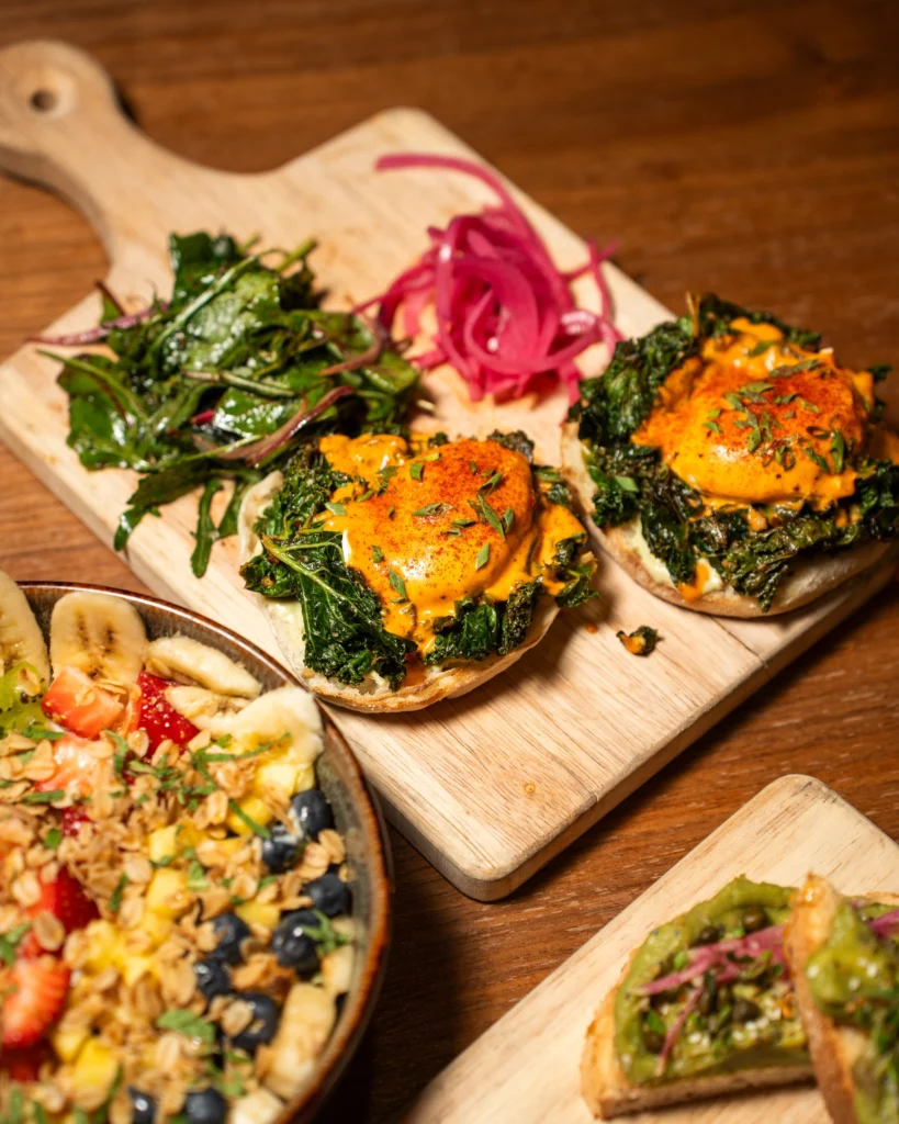 Florentine eggs on sauteed kale with a paprika hollandaise beside a fruit bowl